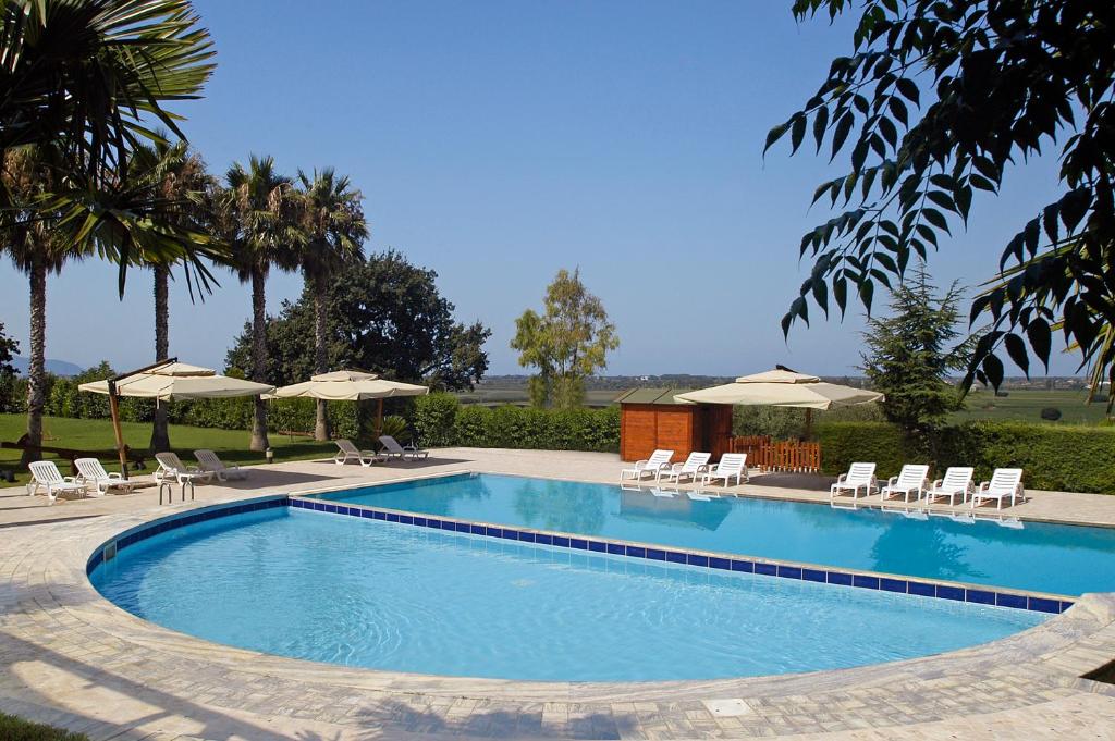 a large swimming pool with chairs and umbrellas at Residenza Giancesare Family Apartments in Paestum