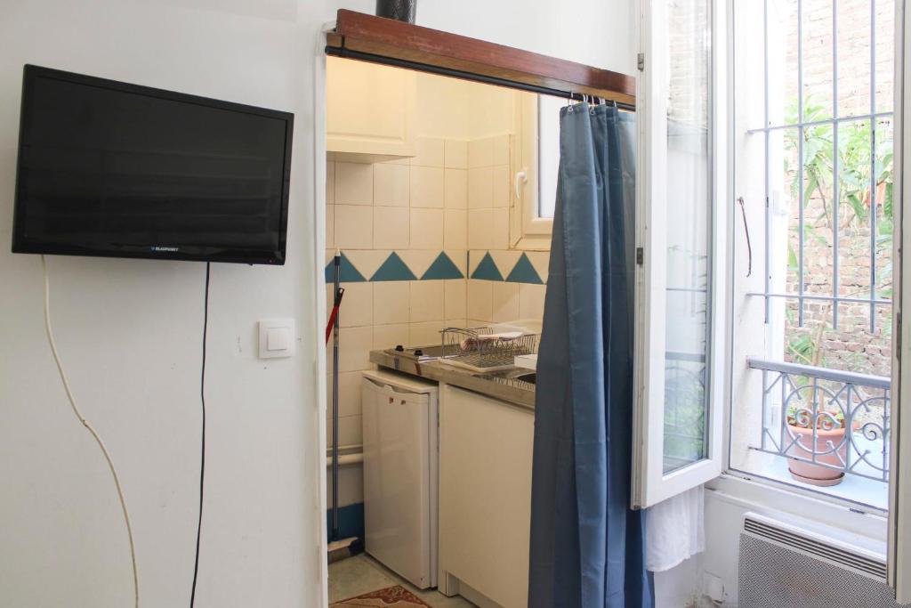 małą kuchnię z telewizorem i oknem w obiekcie Bright studio located near Paris w mieście Pantin