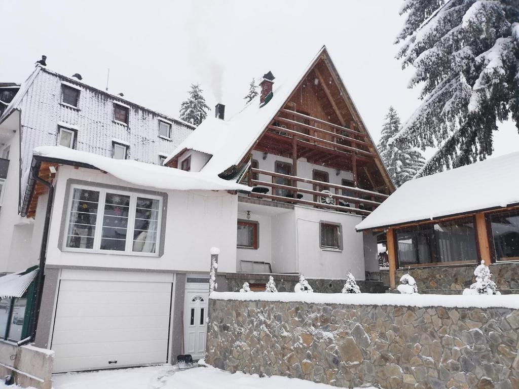 uma casa com um telhado coberto de neve com uma garagem em Apartments Mountain Joy em Travnik
