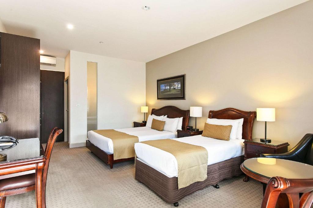 ein Hotelzimmer mit 2 Betten und einem Schreibtisch in der Unterkunft Quality Inn Heritage on Lydiard in Ballarat