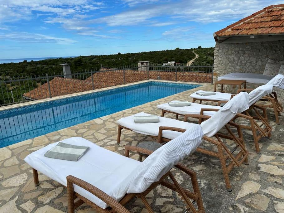 a group of tables and chairs next to a swimming pool at Paradise cottage in Vinišće