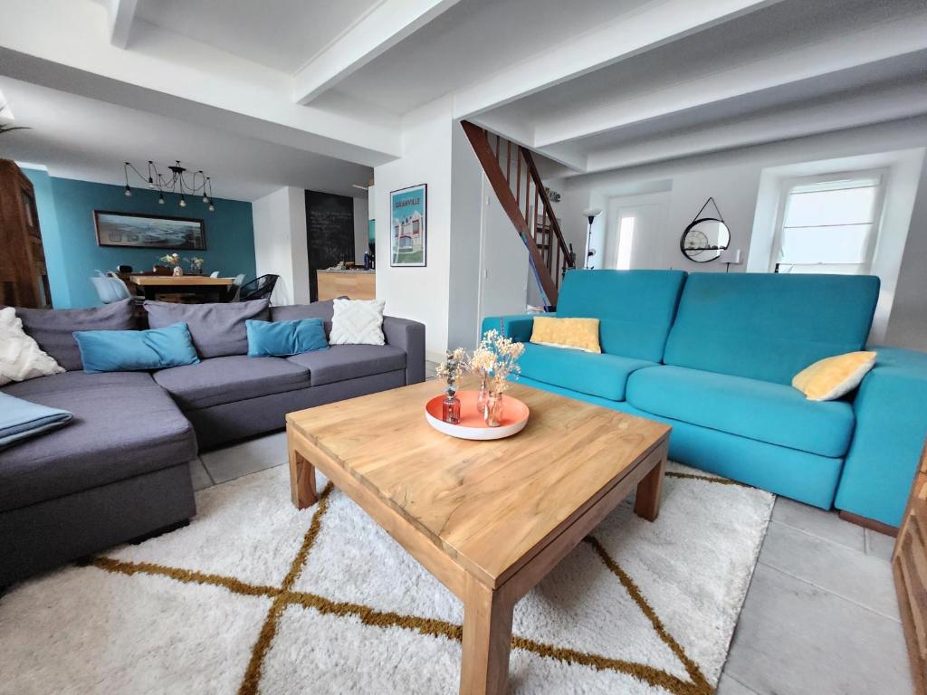 a living room with blue couches and a coffee table at Maison cosy 115m² près de la mer in Hauteville-sur-Mer