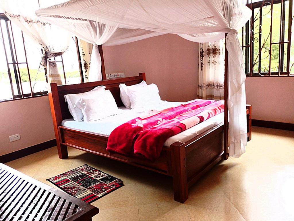 Bett mit Baldachin in einem Zimmer mit Fenstern in der Unterkunft UPENDO MANYARA SAFARI LODGE in Mto wa Mbu