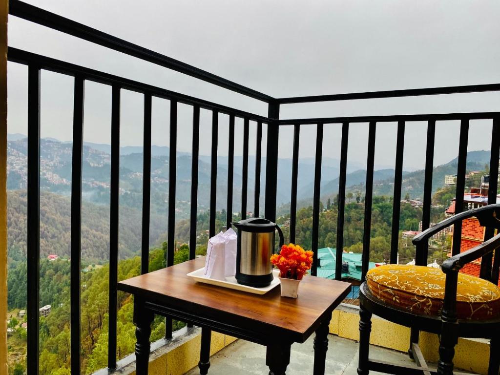 - une table avec une cafetière sur le balcon dans l'établissement Hotel Aachman Regency with Rooftop Terrace, à Shimla