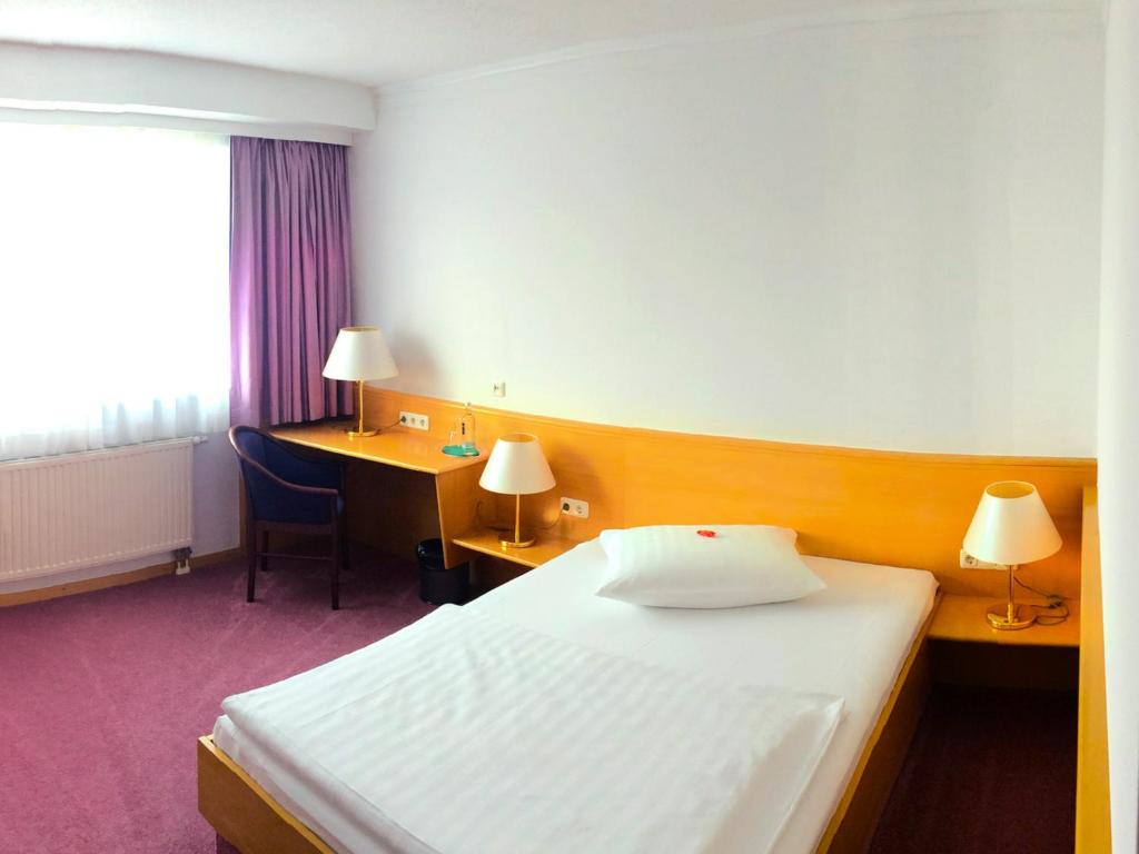 a hotel room with a bed and a desk and a bed at Hotel Bavaria Brehna in Brehna