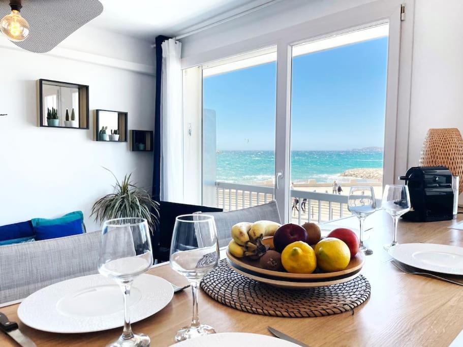 une table avec un bol de fruits et des verres à vin dans l'établissement Calypso face à la mer - Plages et port, à Marseille