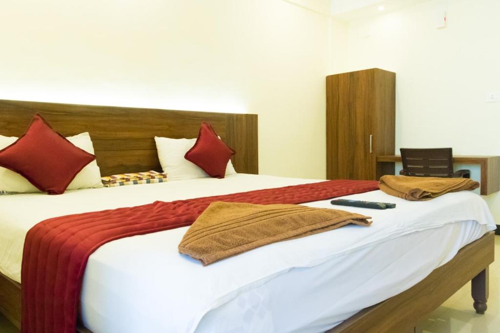 a bedroom with a large bed with red pillows at KRR Grand inn in Coimbatore