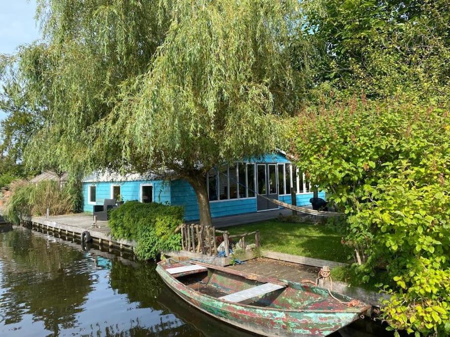ein blaues Haus mit einem Boot im Wasser in der Unterkunft Beautiful house on an island near Amsterdam 