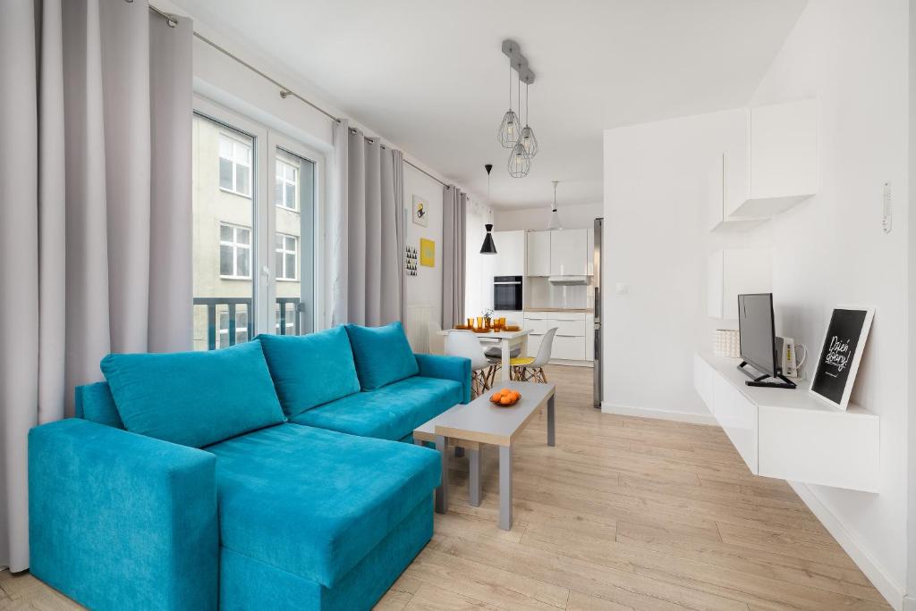 uma sala de estar com um sofá azul e uma mesa em Bulwar Piastowski Chic Apartment em Szczecin
