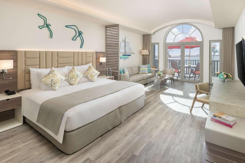 a bedroom with a large bed and a living room at JA Palm Tree Court, Dubai in Dubai