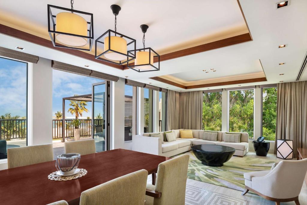 a dining room with a table and a living room at JA Palm Tree Court, Dubai in Dubai