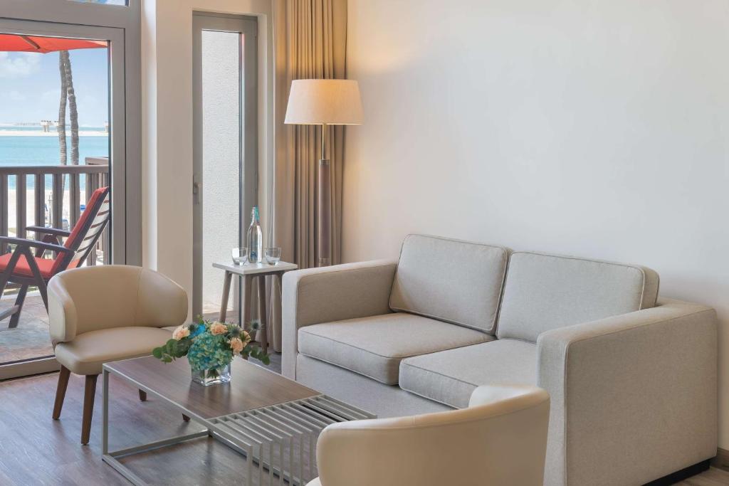 a living room with a couch and chairs and a table at JA Palm Tree Court, Dubai in Dubai