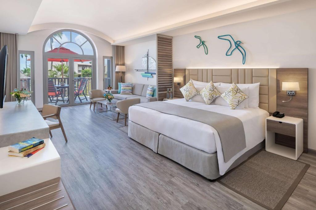 a bedroom with a large bed and a living room at JA Palm Tree Court, Dubai in Dubai