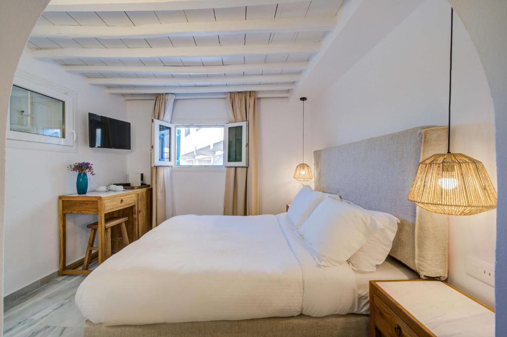 a bedroom with a large white bed and a window at Hotel Madalena in Mýkonos City