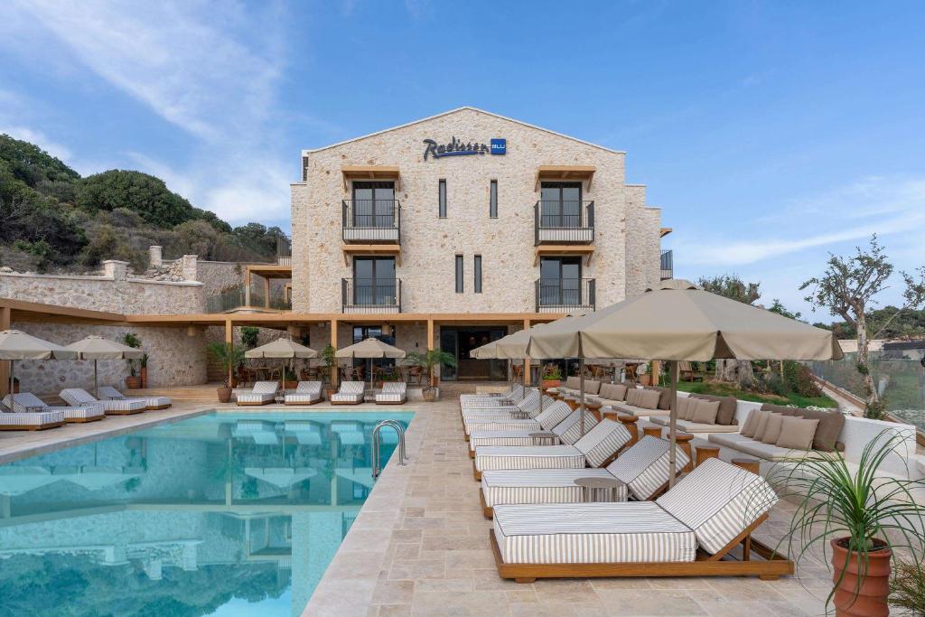 a hotel with a pool with lounge chairs and umbrellas at Radisson Blu Hotel, Kas in Kaş