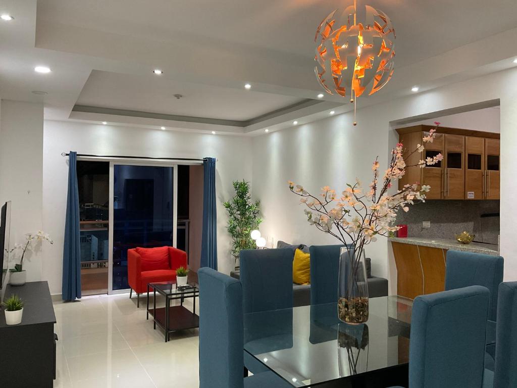 uma sala de estar com uma mesa de vidro e cadeiras azuis em Charming Apartment near Airport and Beaches em Ensanche Savica de Mendoza