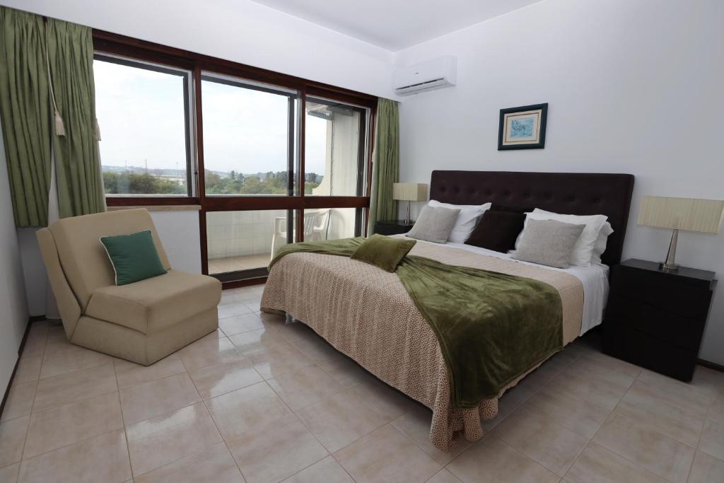 1 dormitorio con cama, silla y ventana en Alvor Beach Front Line Bay, en Alvor