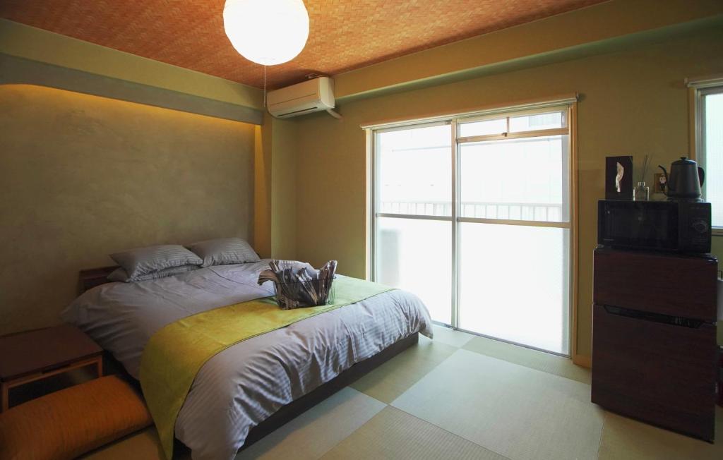 - une chambre avec un lit et une grande fenêtre dans l'établissement 抹茶庵世田谷東京 Matcha-An Setagaya Tokyo, à Tokyo
