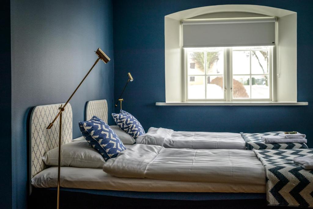 a bed in a blue room with a window at Ericsbergs Slott in Katrineholm