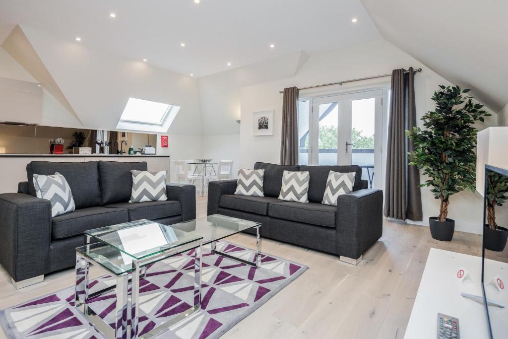 een woonkamer met 2 banken en een glazen tafel bij Roomspace Serviced Apartments- Lyons House in Surbiton