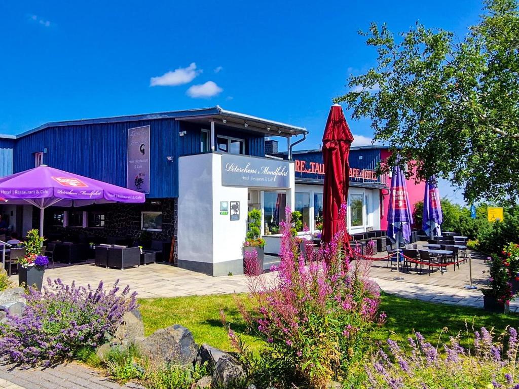 un bâtiment avec des parasols violets dans un jardin dans l'établissement Peterchens Mondfahrt - Wasserkuppe, à Gersfeld