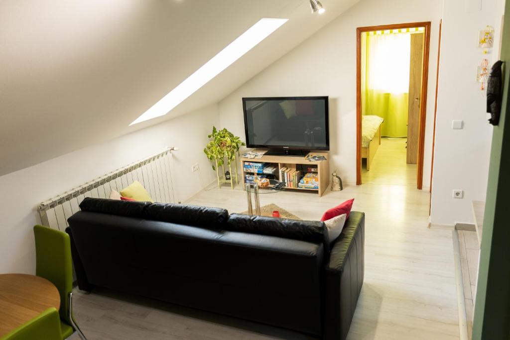 sala de estar con sofá negro y TV en Sunny day apartments, en Sveta Nedjelja