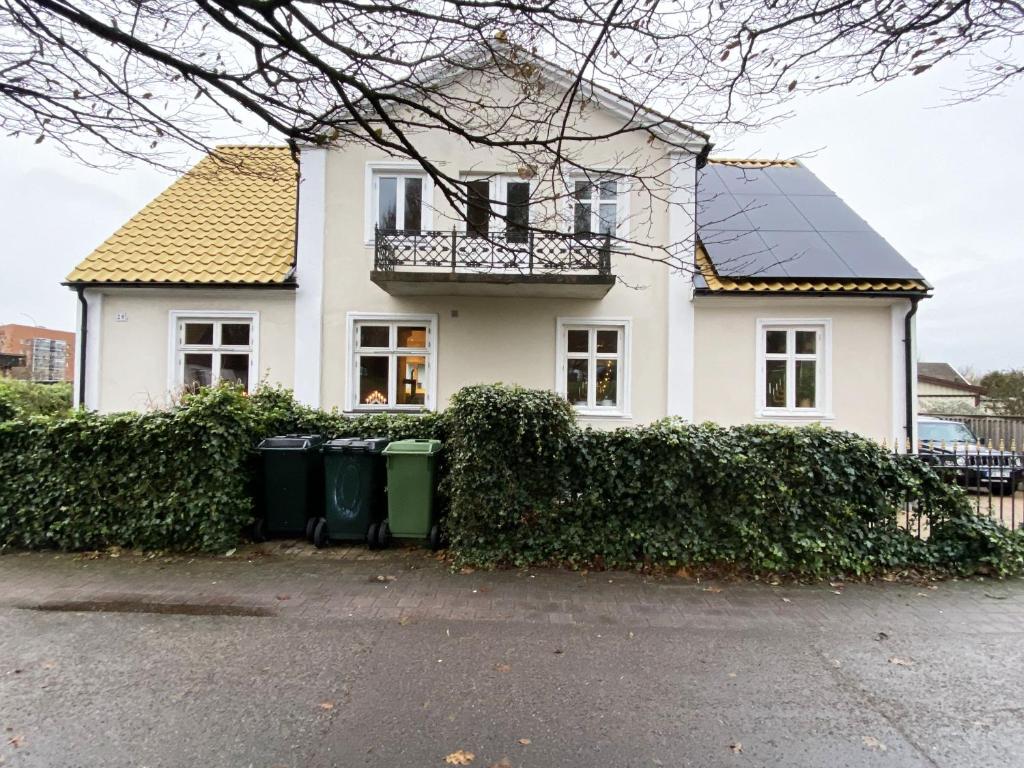 une maison blanche avec deux poubelles devant elle dans l'établissement Holiday home in central Hoganas, à Höganäs