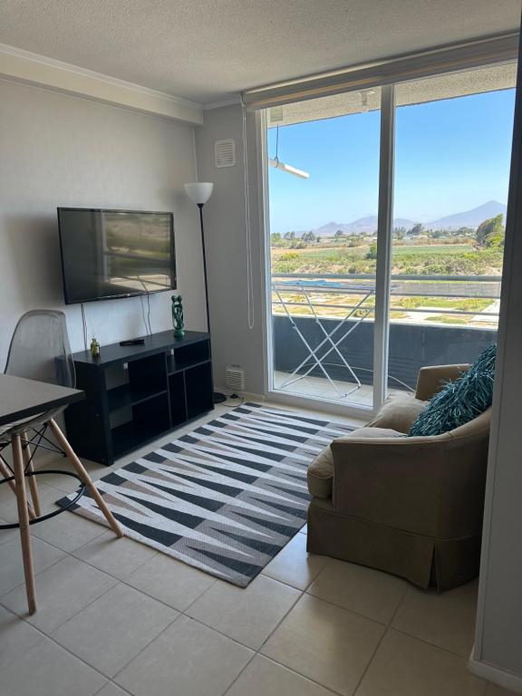 a living room with a couch and a large window at Condominio Río Elqui in La Serena