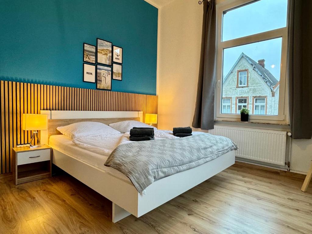 a bedroom with a bed and a large window at Charmante Altbauwohnung an der Kesselschleuse 2 in Emden