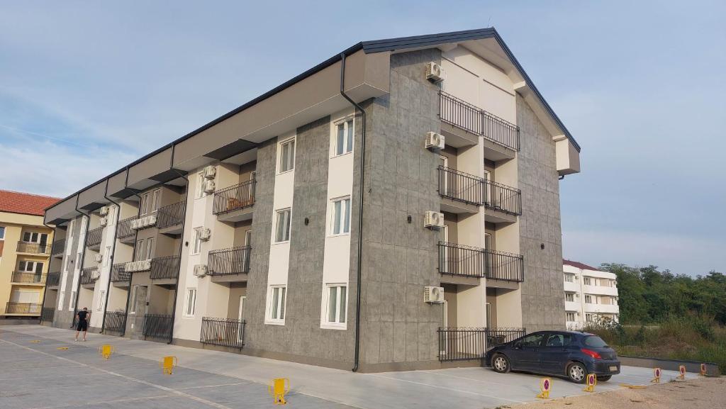 un bâtiment avec une voiture garée sur un parking dans l'établissement Apartman Iris Srebrno jezero, à Veliko Gradište