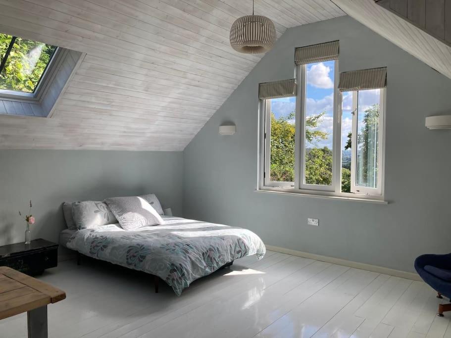 a bedroom with a bed and two windows at Bright, airy Annex in village with stunning views in Stroud