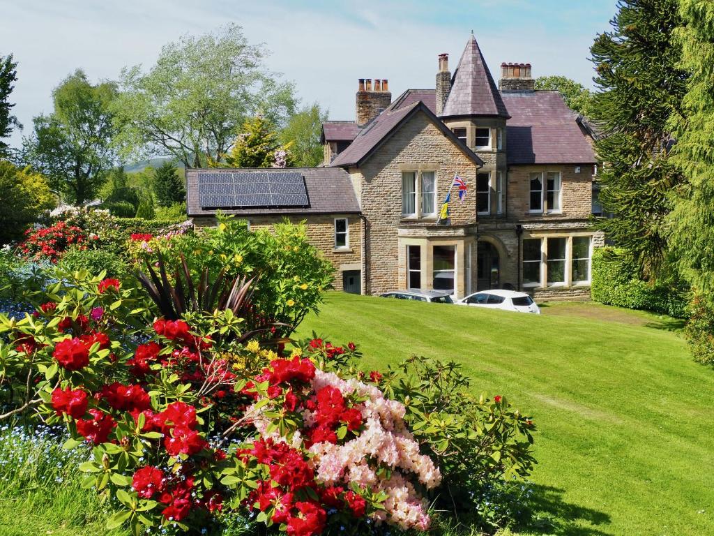 an old house with a bunch of flowers in the yard at Ashfield House in Pateley Bridge