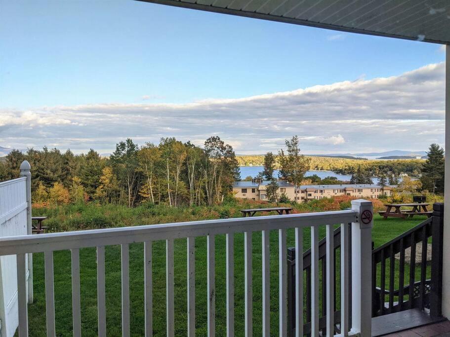 a balcony with a view of a lake and trees at Cute Lower Level Cedar Lodge Room with Balcony & Lake Views! in Laconia