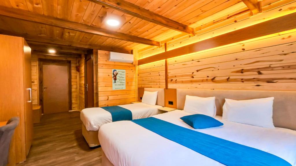 two beds in a room with wooden walls at Nani Boutique Hotel & Bungalow in Çamlıhemşin