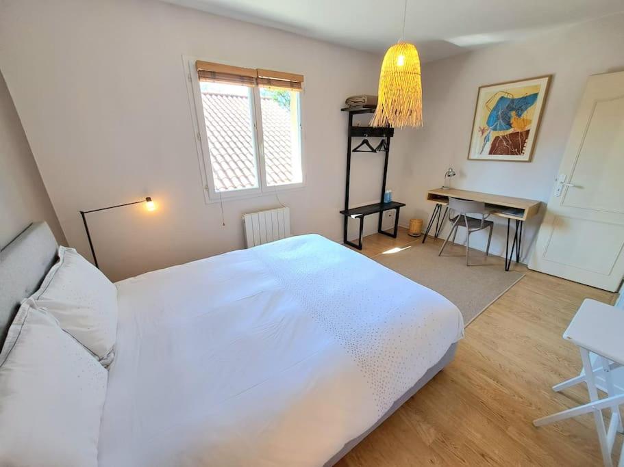 Schlafzimmer mit einem großen weißen Bett und einem Schreibtisch in der Unterkunft Maison au calme . 5ième arr . Ouest Lyonnais in Lyon