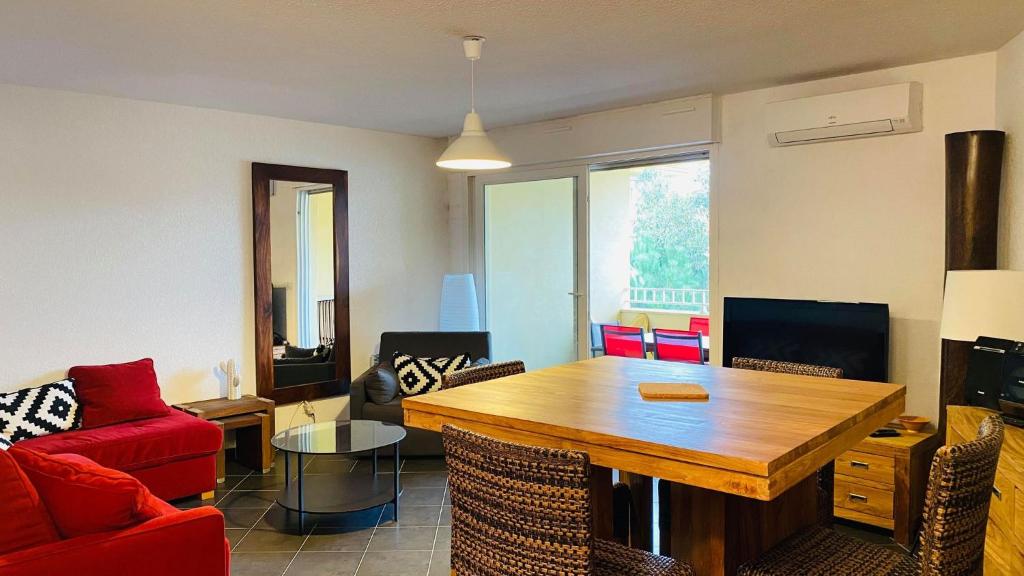 - un salon avec une table en bois et un canapé rouge dans l'établissement Appartement Punta Rossa Calvi, à Calvi