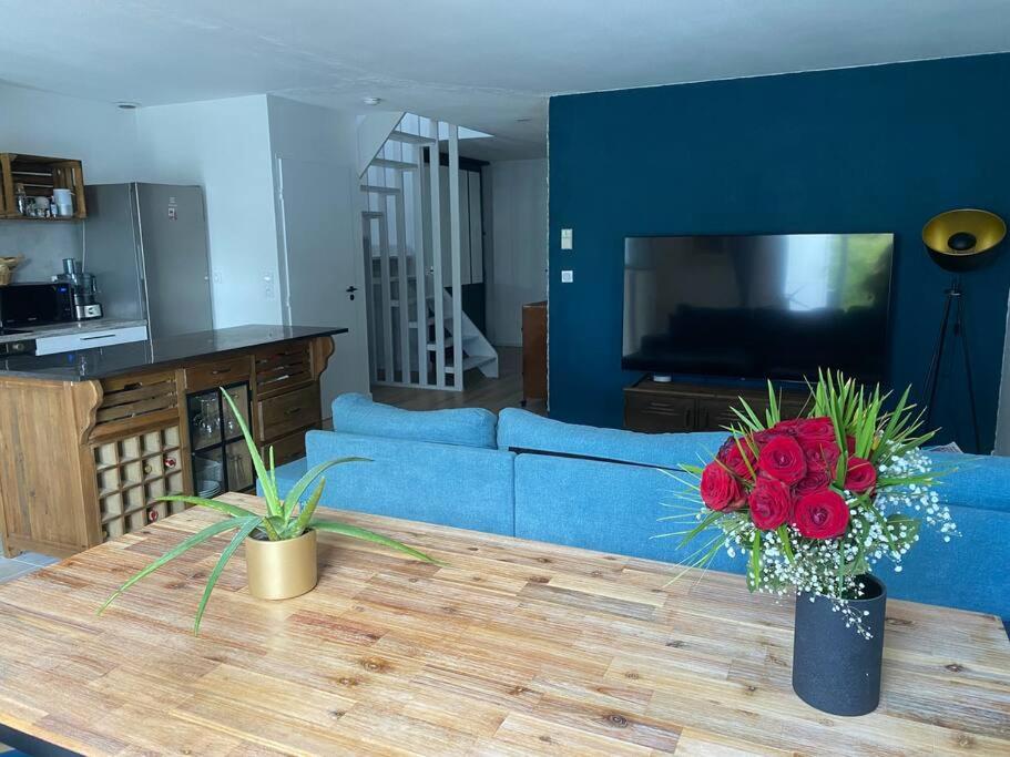 a living room with a blue couch and a table with flowers at Location de charme in Le Haillan