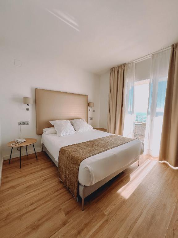 a bedroom with a large bed and a large window at FAY Victoria Beach in Rincón de la Victoria