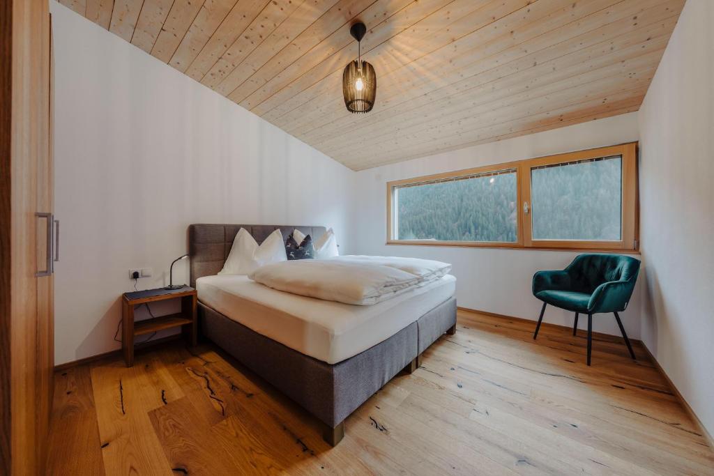 a bedroom with a bed and a green chair at Appartement Anemone in Sankt Gallenkirch