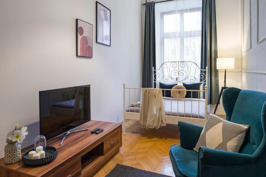 WAWELOVE ROYAL spacious 2 bedroom apt 1 min to Main Sq! في كراكوف: غرفة معيشة مع تلفزيون وسرير أطفال