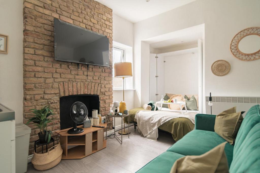 a living room with a couch and a brick wall at Livestay-Studio Apartments in London Green Lanes in London
