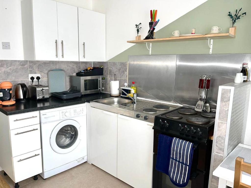 a kitchen with a stove and a washing machine at Comfortable and convenient 1-Bed Apart in Romford in Romford