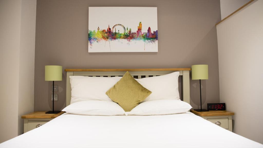 a bedroom with a white bed with two lamps at Barbican Serviced Apartments in London