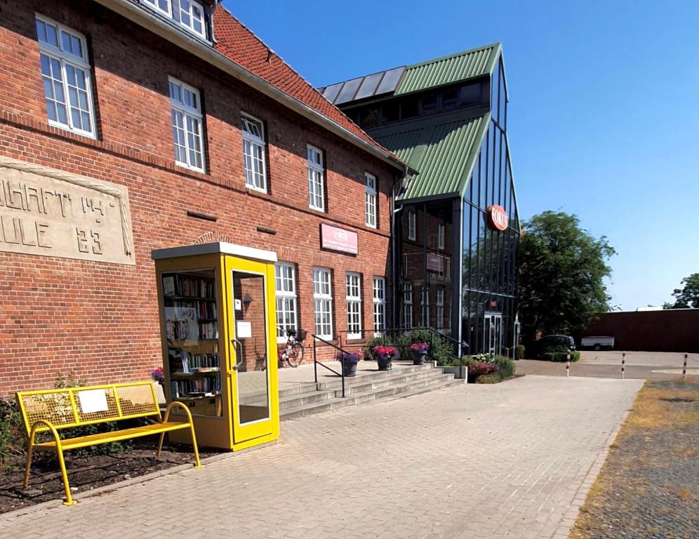 a yellow phone booth in front of a brick building at Hotel Fokus in Emsbüren