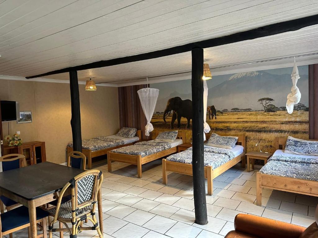 Zimmer mit 4 Betten, einem Tisch und einem Gemälde in der Unterkunft Villa -Guesthousejane & Apartments in Naivasha
