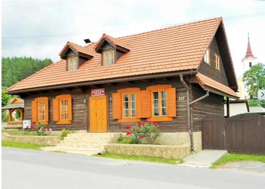 a small wooden house with orange doors on a street at Penzion Hron in Brezno