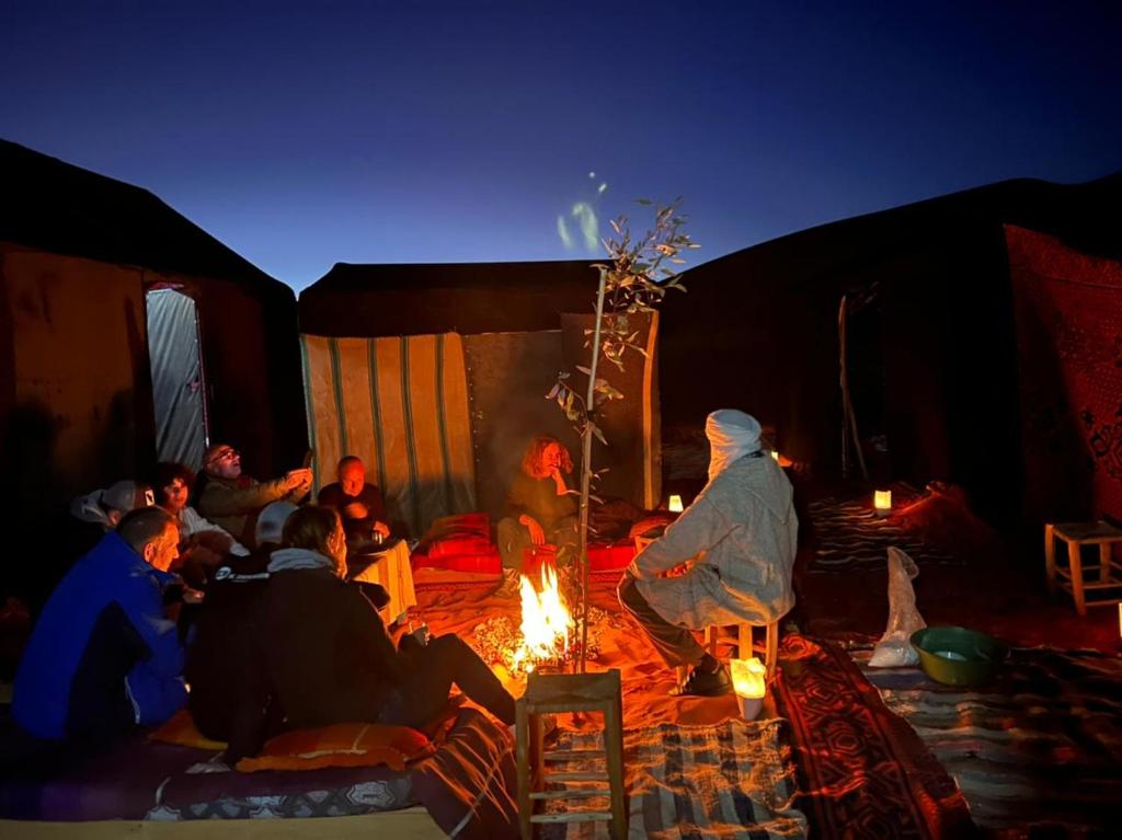 un grupo de personas sentadas alrededor de un fuego en una tienda en Gambe Camp en Hassilabied