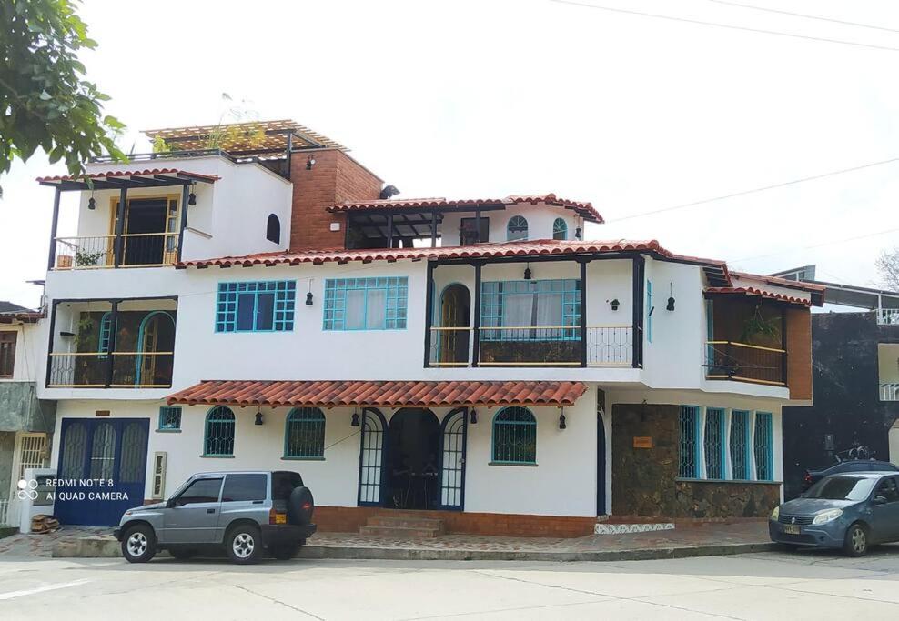 un gran edificio blanco con coches estacionados frente a él en Casa Turística Líbano, en Líbano