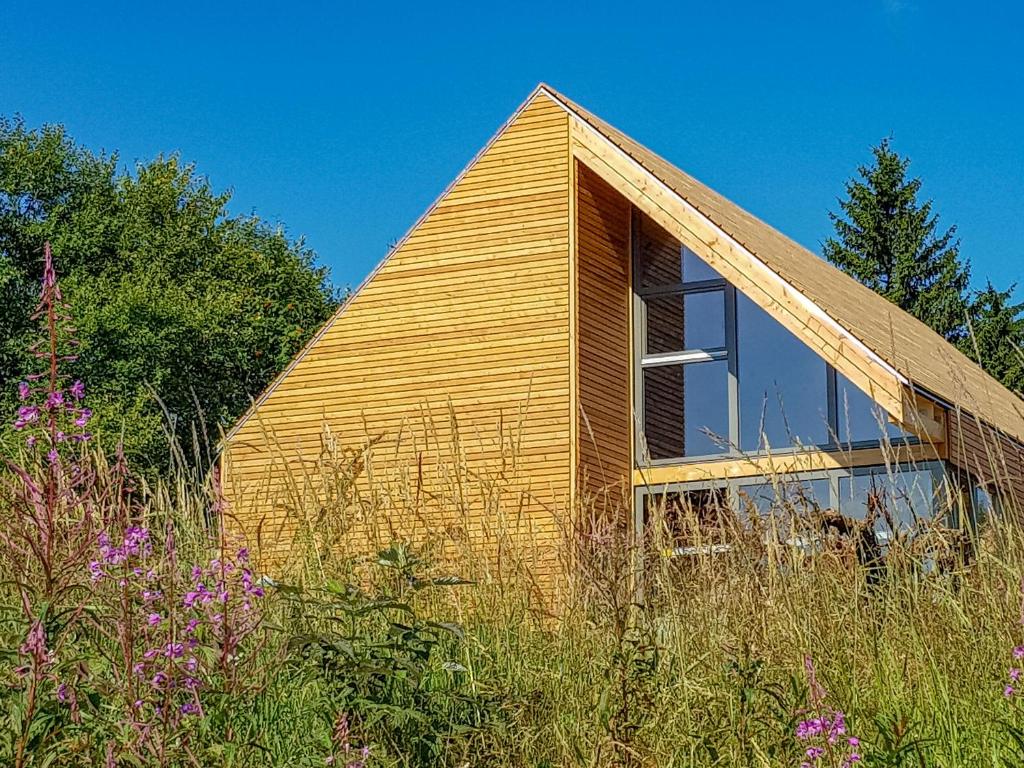 ein Holzhaus mit einem großen Fenster auf einem Feld in der Unterkunft Feriendorf Wasserkuppe 