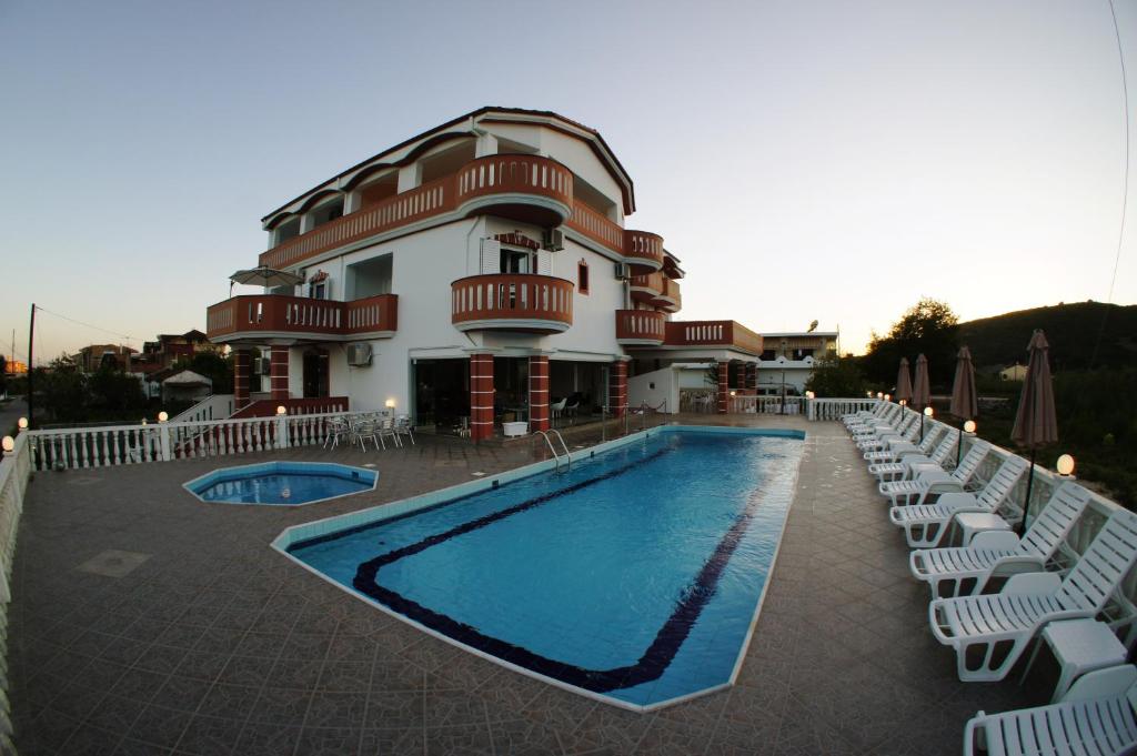 un hotel con piscina, sillas y un edificio en Hotel Alexandros en Ammoudia